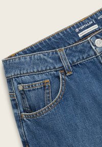 Ceinture de jeans en denim bleu avec passants de ceinture, poche à monnaie, bouton en métal et étiquette indiquant "Tom Tailor" et "Made with organic cotton."