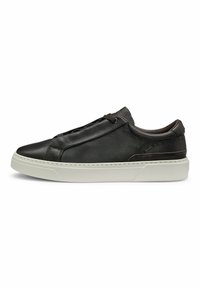 Black leather sneaker with a minimalist design, elastic laces, and a textured finish. Features a white rubber sole and subtle stitching details.