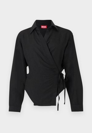 Chemise noire à manches longues de style portefeuille avec col et liens latéraux, présentant un petit logo brodé près de la poitrine et une étiquette de marque rouge à l'intérieur du col.
