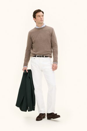 Brun trøje, lyseblå skjorte, hvide jeans, grøn jakke i hånden, brune loafers. Simple design, blød tekstur, neutral farvepalet.