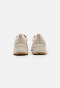 Lys beige sneakers med en kombinasjon av glatt lær og myk semsket skinn, med en tykk hvit midtsåle og strukturerte gummisåler.