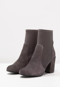 Szare botki za kostkę wykonane z zamszu i siateczki, cechujące się blokowym obcasem oraz bezszwowym designem z teksturowanym wykończeniem po bokach.