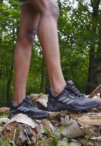 Sorte turskoer har et robust design med grå detaljer og hvite striper. De står på en strukket tresoverflate i et skogkledd miljø.