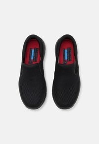 Zapatos de trabajo negros sin cordones con parte superior de malla texturizada, plantillas de espuma viscoelástica y suelas antideslizantes, con un forro interior rojo.