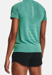 Camisa deportiva de manga corta en verde, con tejido texturizado y un patrón sutil, además de un pequeño logo en el lado inferior.