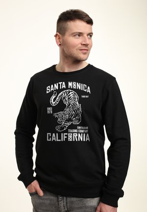 Sort sweatshirt med et stort hvidt tiger grafik og teksten "SANTA MONICA". Designet inkluderer slidte bogstaver og crew neck stil.