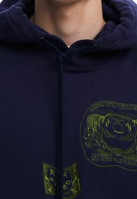 Granatowa bluza z kapturem wykonana z bawełny, z zielonymi grafikami, w tym okrągłym motywem i czaszką, z regulowanym sznurkiem.