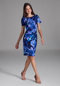 Robe à imprimé floral avec des couleurs bleues et noires, manches courtes, silhouette ajustée et longueur genoux. Texture de tissu lisse.