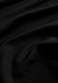 Sort stof med en glat, struktureret overflade, der har subtile folder og rynker i et let, strækbart materiale.