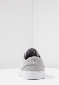 Graue Wildledersneaker mit einem flachen Design, weißer Gummisohle und genähten Akzenten. Verfügt über ein Logo an der Seite und einen gepolsterten Kragen.