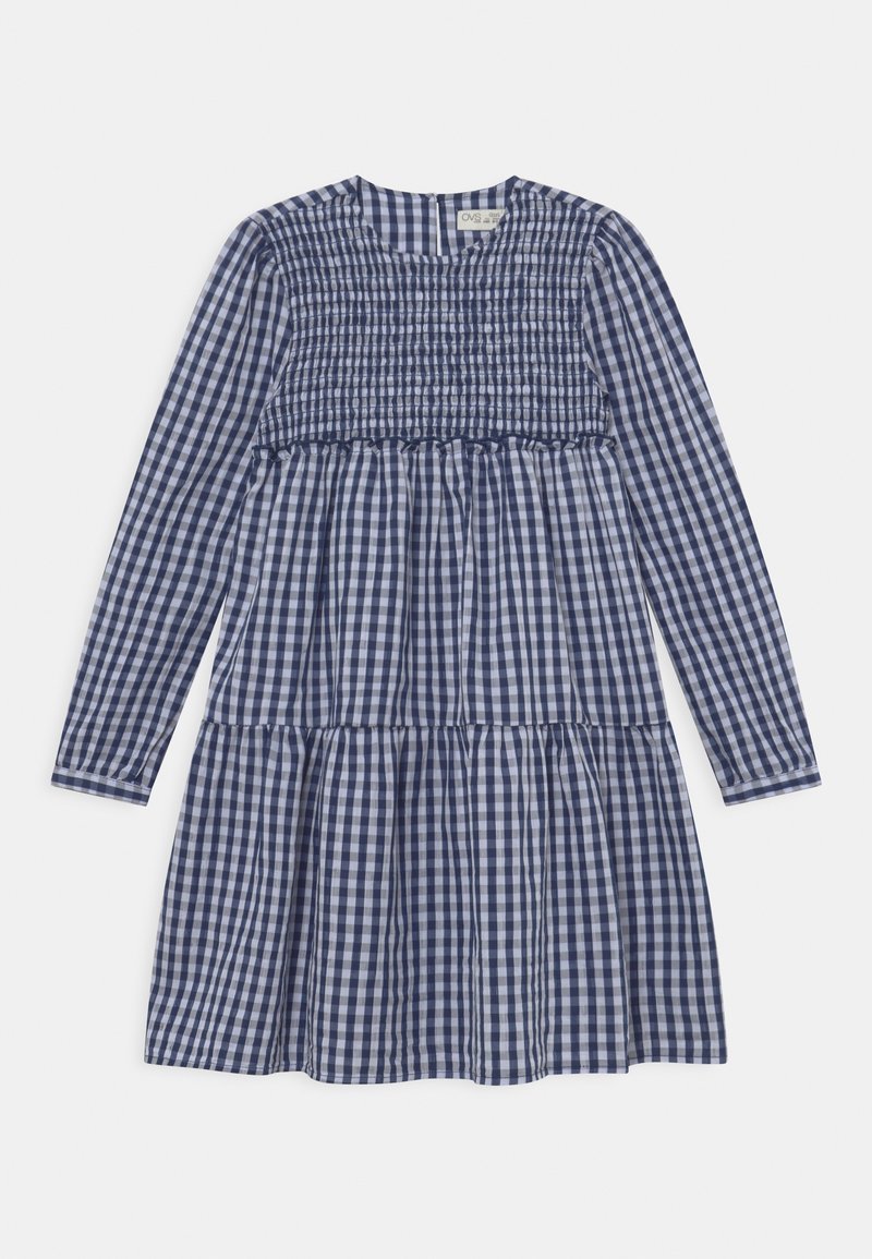 Robe à manches longues bleue et blanche à carreaux vichy avec un corsage smocké et une jupe à volants, posée à plat sur un fond blanc.