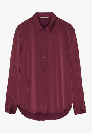 Burgunderfarbene, langärmelige Bluse aus glattem Satinmaterial mit Kragen, Knopfverschluss und abgerundetem Saum. Die Knöpfe sind in der gleichen Farbe wie der Stoff.