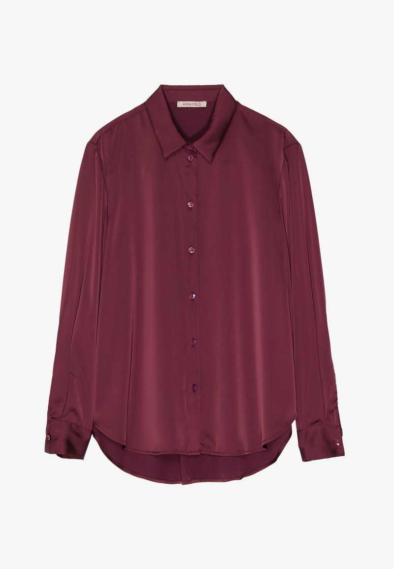 Bordo bluza dugih rukava od glatke satenske tkanine s ovratnikom, prednjim kopčanjem na gumbe i zaobljenim rubom. Gumbi su u boji tkanine.