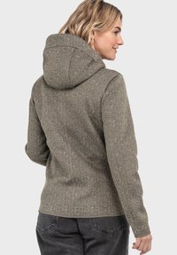 Hoodie-Jacke aus einem strukturierten braunen Stoff, mit tailliertem Design und einem Saum, der an den Hüften sitzt. Die Rückansicht zeigt eine Schlichtheit im Stil.
