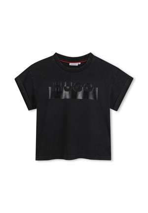 T-shirt noir oversize en coton, avec un logo "HUGO" noir brillant sur le devant. Encolure ronde avec des manches courtes retroussées.