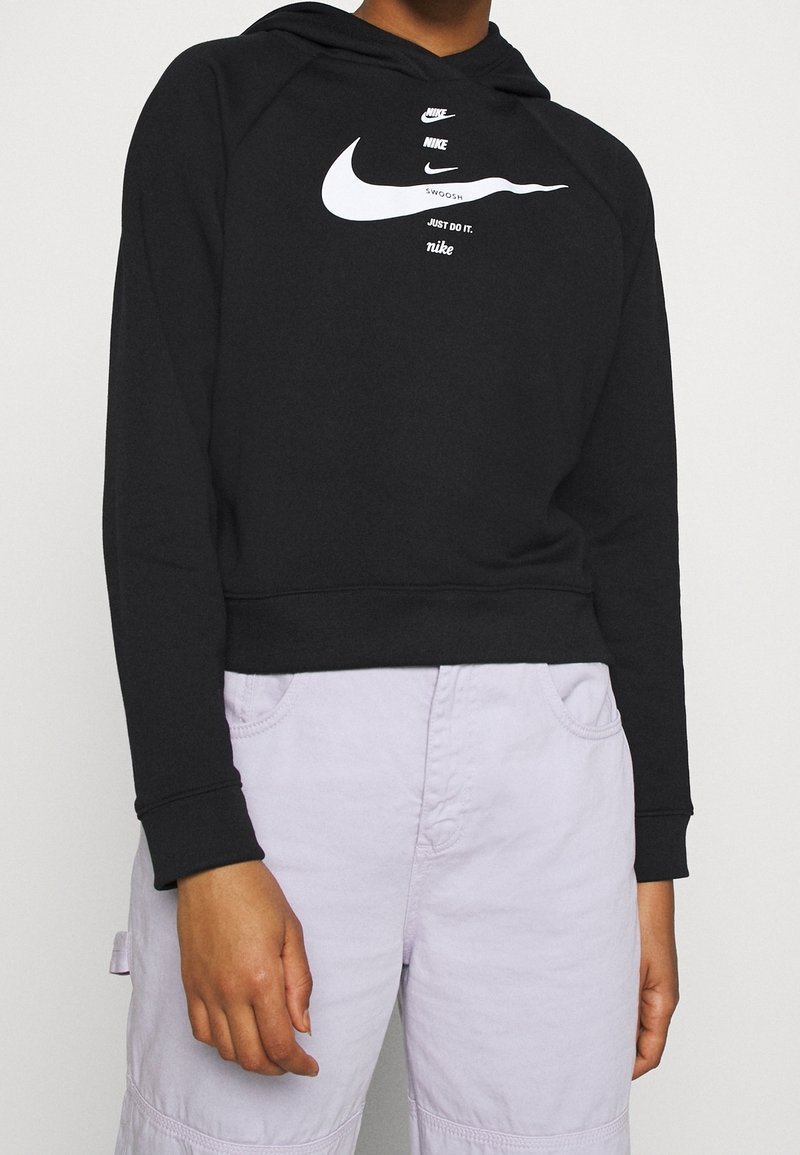 Schwarze kurze Kapuzenjacke aus weichem Stoff, mit einem weißen Nike-Logo und dem Text "Just Do It". Lange Ärmel, Design mit Kängurutasche.