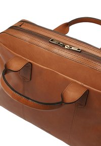 Läder tote i beige med dragkedjestängning, dubbla handtag och beige sömmar. Har en polerad metalldragkedja som accent. Slät textur.