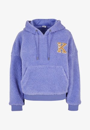 Lila bolyhos kapucnis pulóver, zsinóros kapucnival, elülső zsebbel és struktúrált felülettel. Arany és krém színű hímzett "K" betűvel díszítve.
