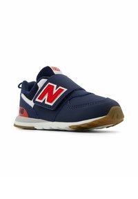 Zapatilla navy con acentos en rojo y blanco, una correa de Velcro, secciones de malla y una suela de goma. Presenta una puntera redonda y un acabado texturizado.