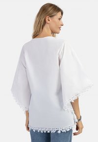 Tunică albă cu mâneci largi, având dantelă la margine și la manșete. Material ușor, cu o croială lejeră, ideală pentru purtatul casual.