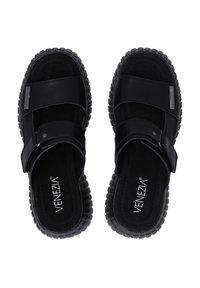 Zwarte sandalen met een gestructureerde bovenkant, voorzien van kruisriemen en een gevoerde zool. Opvallende details zijn een zilveren accent op de riem.