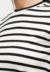 Μπλούζα με μαύρες και λευκές ριγέ, στρογγυλή λαιμόκοψη, με οριζόντιες ρίγες και απαλή υφή υφάσματος.