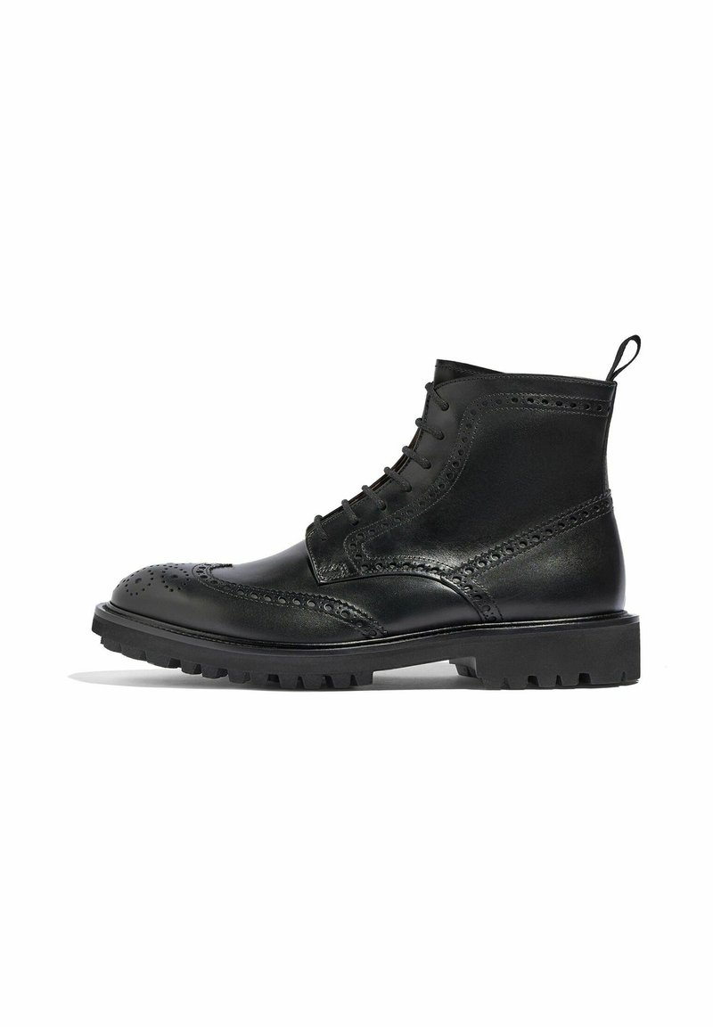Bota de cuero negro con detalles de brogue, diseño de cordones y una tira de agarre; presenta una suela gruesa y resistente para una tracción mejorada.