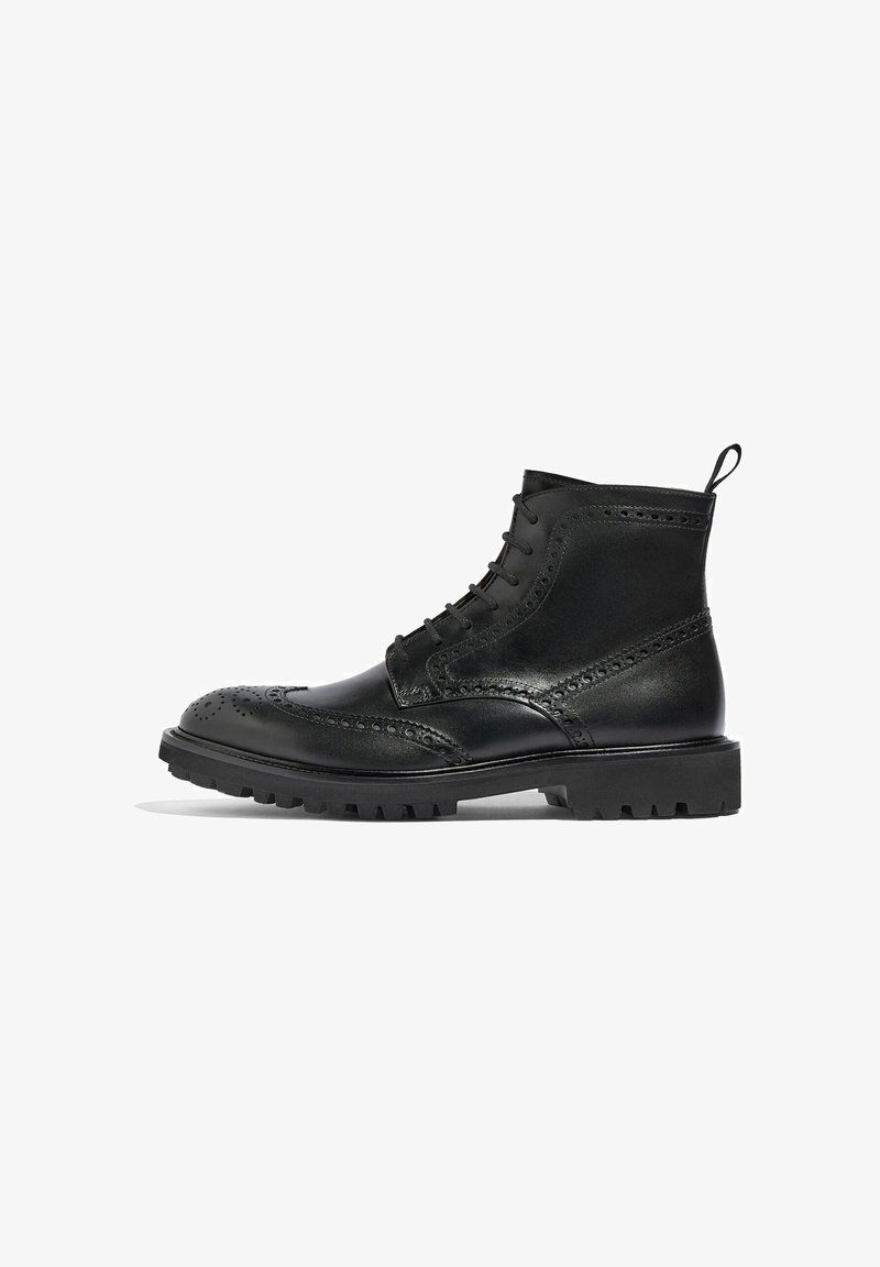 Bota de cuero negro con detalles de brogue, diseño de cordones y una tira de agarre; presenta una suela gruesa y resistente para una tracción mejorada.