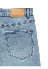 Šviesiai mėlyni džinsai iš denim audinio su šviesiai rudos odos prekės ženklu ant juosmens ir standartiniu galiniu kišeniu su kontrastingais siūlais.