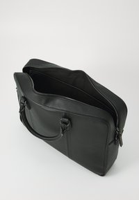 Zwarte lederen laptoptas met textuur, dubbele handgrepen en ritssluiting. Het interieur is gevoerd met zwarte stof, ruim en onopgesmukt.