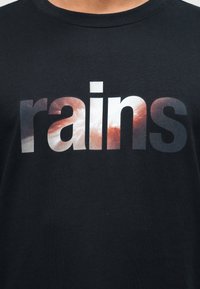 Μαύρο πουκάμισο με μεγάλο κείμενο «rains» γεμάτο με μοτίβο συννεφιασμένου ουρανού σε αποχρώσεις λευκού, πορτοκαλί και γκρι στο στήθος.