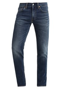 Męskie niebieskie dżinsy, z klasycznym prostym krojem, pięcioma kieszeniami i subtelnym przetarciem na udach, które dodaje faktury.