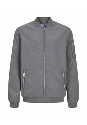 Veste bomber légère grise avec un col haut, fermeture éclair à l'avant et poches latérales, assortie à un pantalon vert ample et des baskets noires.