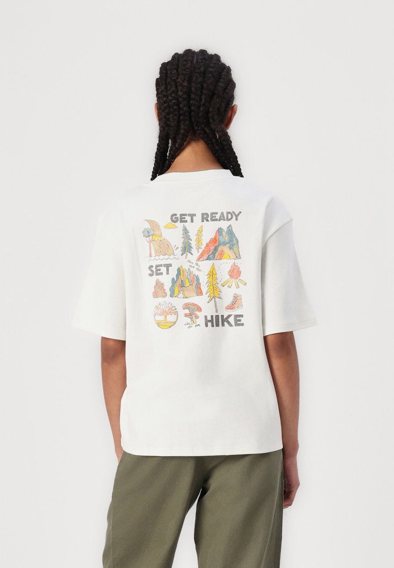 T-shirt en coton blanc à coupe décontractée, avec un graphique coloré sur le thème de la nature dans le dos portant le texte "PRENEZ LA ROUTE, PRÊTS, PARTEZ".