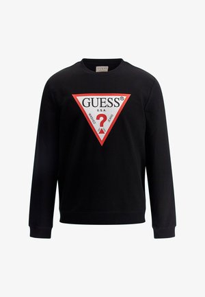 Fekete pulóver hosszú ujjal, piros háromszöglogóval, amelyen a "GUESS," "U.S.A" és egy kérdőjel található a közepén.