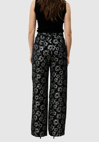 Zwarte brede broek met wijde pijpen en een zilveren bloemenpatroon, voorzien van een elastische tailleband en zoom met trekkoord voor verstelbare pasvorm.