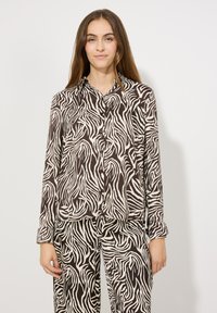 Bruine en crème lange mouwen overhemd met een zebra-streep patroon. Zachte stof, ontspannen pasvorm, borstzak, gecombineerd met bijpassende broek.