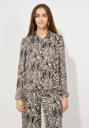 Chemise boutonnée à manches longues brun et crème avec un motif de rayures zèbre. Tissu doux, coupe décontractée, poche poitrine, associée à un pantalon assorti.