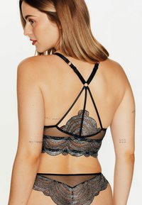 Ensemble de lingerie en maille noire avec des accents en dentelle argentée, bords festonnés complexes, bretelles ajustables et un design délicat.