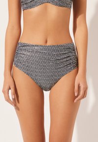 Bikini spodní část s vysokým pasem v černobílé shrnované tkanině s texturovaným vzorem a nařasením po stranách.