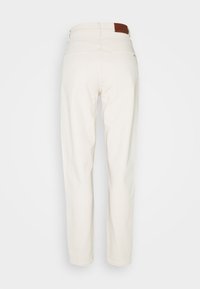 Pantalones de mezclilla blanca con un ajuste recto, diseño de cinco bolsillos y una etiqueta de marca de cuero marrón en la parte posterior de la cintura. Textura suave, estilo minimalista.