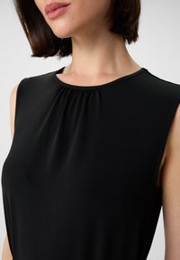 Schwarzes ärmelloses Oberteil mit gerafftem Ausschnitt, aus glattem Stoff gefertigt, mit rundem Kragen und zurückhaltendem Design.