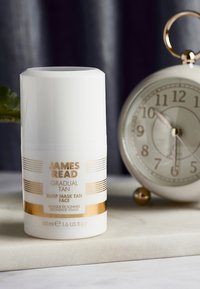 Bottiglia cilindrica bianca con dettagli dorati e testo nero. L'etichetta indica "James Read Gradual Tan Sleep Mask Tan Face," dimensione 50 ml.
