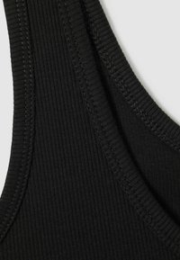 Czarny prążkowany materiał o gładkiej fakturze, z szerokimi ramiączkami i subtelnymi przeszyciami wzdłuż krawędzi.