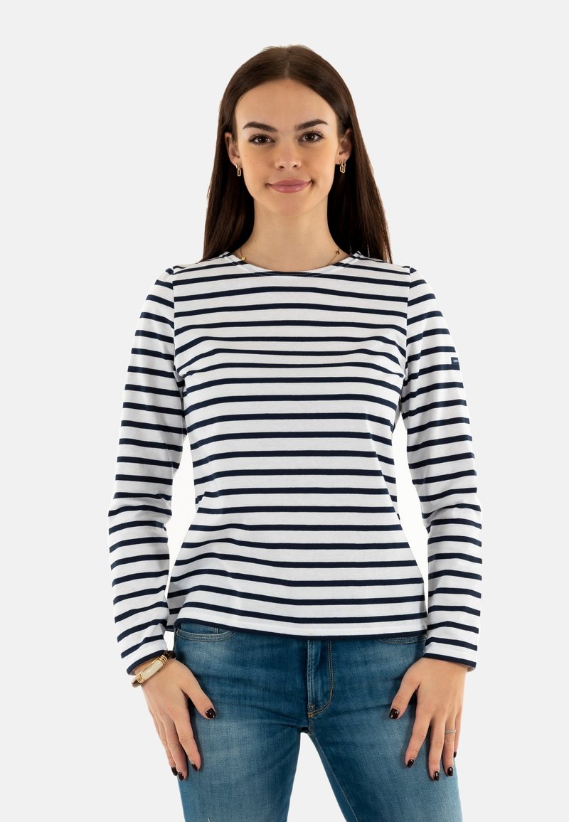 Maglietta a maniche lunghe a righe blu navy e bianche, realizzata in morbido cotone, con scollatura rotonda e silhouette aderente. Abbellita da un piccolo logo.