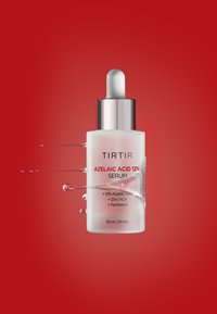 Bottiglia di siero etichettata "TIRTIR Acido Azelaico 12%" con tappo contagocce, spruzzi di liquido, su sfondo rosso solido.