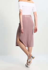 Pencil skirt pink pahlawan lutut dengan belahan samping dan lubang sabuk. Dipasangkan dengan atasan off-shoulder dan sandal bertumit perak. Kain yang halus dan terancang.