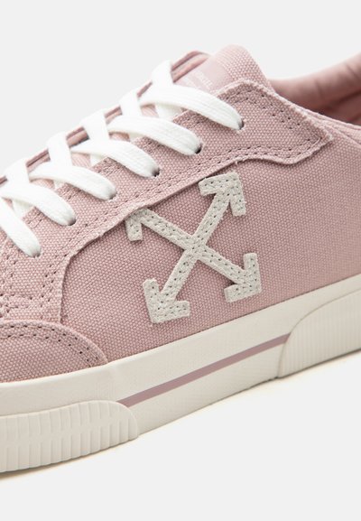 Ανοιχτό ροζ πάνινο αθλητικό παπούτσι με λευκά κορδόνια, λευκή σόλα με ροζ ρίγα και κεντημένο λογότυπο διπλού βέλους στην πλευρά.