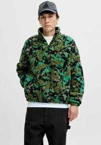 Pull en polaire avec un motif camouflage vert et noir, doté d'un col montant, d'une fermeture éclair quart et d'une coupe décontractée en tissu doux et texturé.