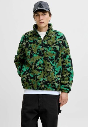 Pull en polaire avec un motif camouflage vert et noir, doté d'un col montant, d'une fermeture éclair quart et d'une coupe décontractée en tissu doux et texturé.